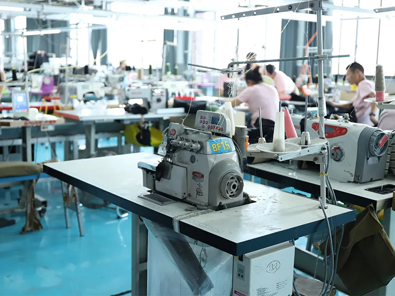 Modern garment workshop with sewing machines and workers, showing WHFrontend’s professional OEM outdoor apparel production process.